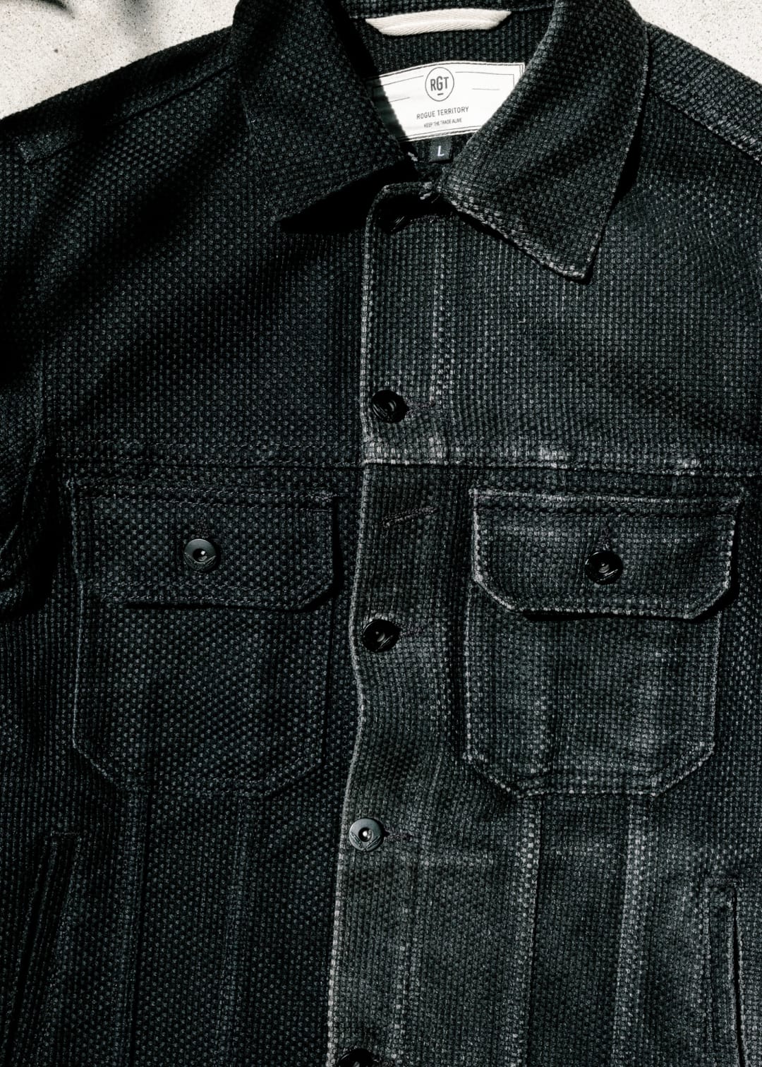 Black denim jacket with button details on a light background